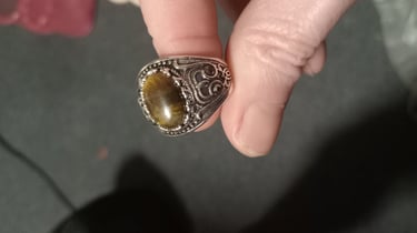 a silver ring with engravings and a yellow cats eye stone