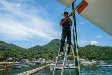 Technician on a ladder installing a cctv cable at Warloka Pesisir, NTT
