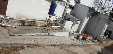 Industrial building exterior featuring large metal grease trap covers and a blue water storage tank.