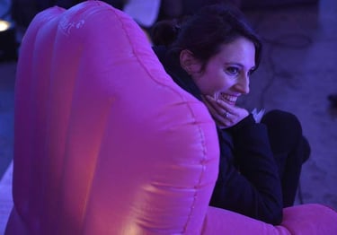 Lou Raya sourit dans un fauteuil rose | Les Camps de l'Amor | David Noir | Photo Karine Lhémon