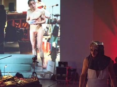 David Noir grimé devant une photo de lui nu | Retour sur investissement | D. Noir | C. Imbs | B. Bousquet