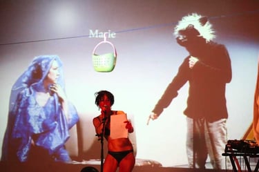 Marie au micro devant une photo de l'Annonciation où l'ange est un mouton | Mobil'Homme | David Noir | Photo Bernard Bousquet