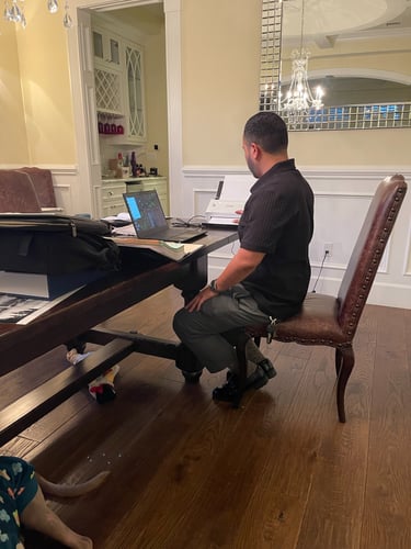 A man working on a laptop and document scanner at a home office dining table.