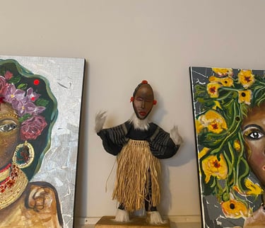 Poupée africaine artisanale avec une jupe en raphia entre deux peintures de portraits floraux coloré