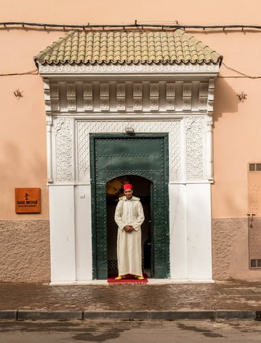 A berber man in traditional outfit welcoming guests into a restaurant