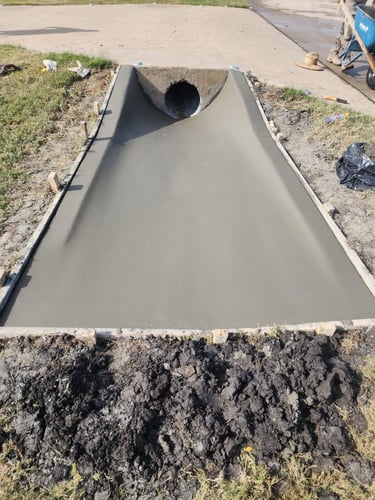 Freshly poured concrete drainage with culvert pipe.