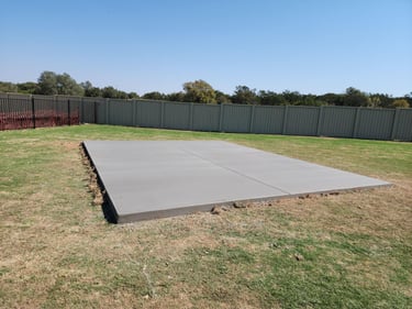 Freshly poured concrete slab in a backyard.