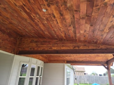Covered patio with stained wood ceiling and beams.