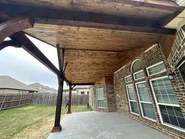 Covered patio with stained wood ceiling and posts.