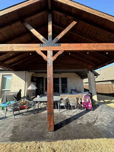 Covered patio with exposed wood trusses and outdoor dining setup.