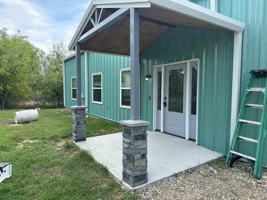 Covered front entry of green metal building.