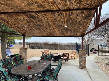 Covered patio with stained wood ceiling and outdoor dining furniture.