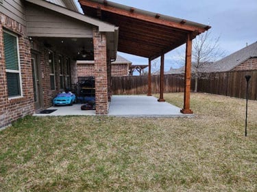 Brick house with a wooden patio cover over a concrete slab.