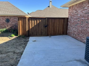 Wooden privacy fence with gate and concrete slab.