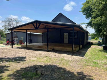 Covered wooden deck with black posts and wood ceiling.