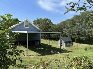 Metal patio cover beside blue house.