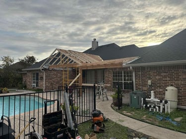 Covered patio under construction with exposed roof framing.