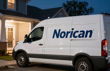 A professional service vehicle with a logo parked outside a North American / US home at night under bright exterior lighting.