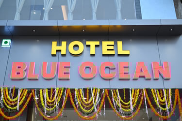 The exterior signage for Hotel Blue Ocean featuring yellow and orange illuminated letters decorated with flower garlands.