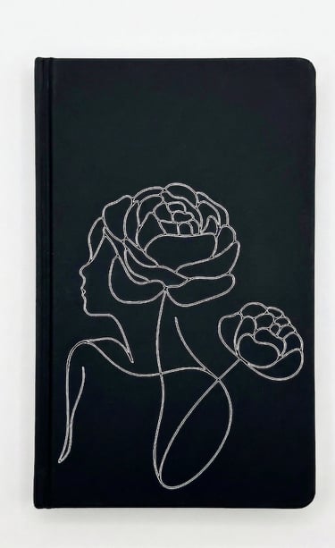Black hardcover journal featuring white line art of a woman's profile and blooming peonies.