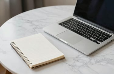Clean photography of a modern laptop and a minimalist notepad on a white marble desk in a South American / Brazilian designer workspace.