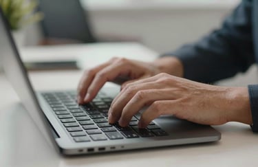 A close-up of professional hands typing on a modern, slim keyboard. Sharp focus, clean desk background, British office context.