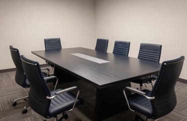 A wide-angle professional photograph of a contemporary North American / US boardroom. A long, polished Dark Navy table is surrounded by ergonomic chairs. The lighting is soft and even, emphasizing a space built for stability and high-level decision making.