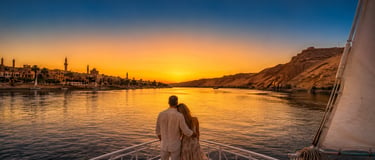 A couple watching a golden sunset over the Nile River from a boat deck in Aswan, Egypt.