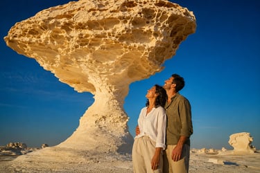 A couple stands by a mushroom-shaped white desert rock formation in Egypt's Farafra depression.