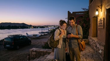 A couple looking at a smartphone outside a Nile View guesthouse in Egypt at sunset.