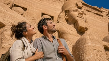 A smiling couple sightseeing at the Abu Simbel temples in Egypt, admiring the massive ancient rock-cut statues.