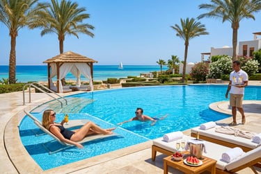 Luxury beachfront resort pool with people relaxing and palm trees overlooking the Red Sea.
