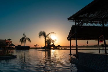 Jolie Ville Hotel resort infinity pool at sunset with a swim-up bar overlooking the Nile River.