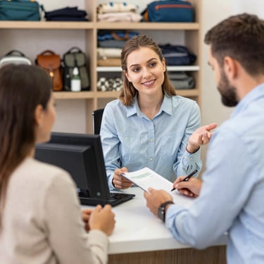 A smiling retail consultant assisting a couple with a contract signing in a modern boutique.