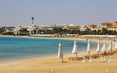 Luxury Sahl Hasheesh beach resort in Egypt featuring white umbrellas on a sandy shore.
