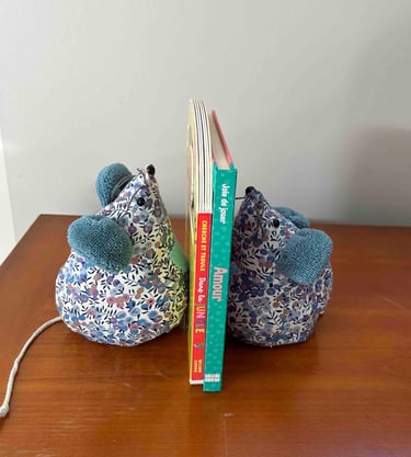Des serre-livres souris en tissu à motifs floraux tenant des livres pour enfants sur un bureau