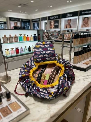 A floral drawstring makeup bag organizer filled with cosmetics on a department store beauty counter.