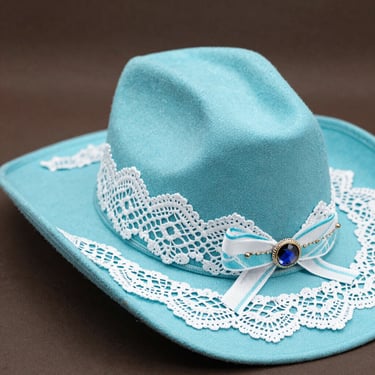 A lively cowboy hat experience at a rustic outdoor wedding with guests smiling and dancing.