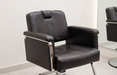 A detail shot of a comfortable, stylish salon chair in a dark #262A2D leather finish, positioned in a bright, modern corner of the salon.