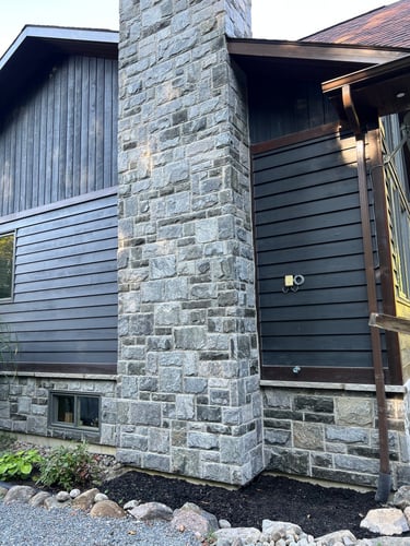 Rustic home exterior featuring a granite veneer square pattern chimney.
