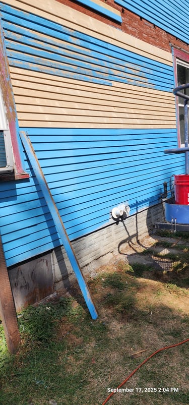 Blue and tan lap siding installation on a residential house exterior with construction tools.
