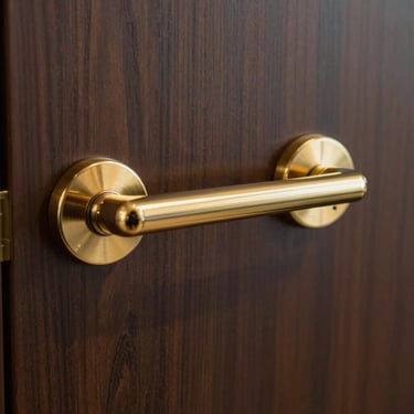 A close-up of a polished gold-toned door handle on a solid dark wood door in a professional North American executive office.