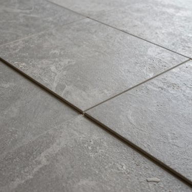 Detailed shot of large-format textured gray tiles being professionally aligned with architectural precision in a high-end California renovation.