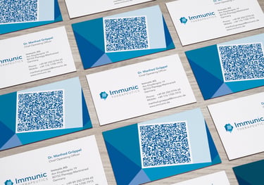 Professional Immunic Therapeutics business cards with QR codes and contact information displayed on a desk.