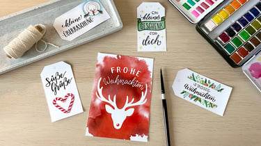 Handmade Christmas gift tags and watercolor holiday cards with reindeer and hand-lettered calligraphy.