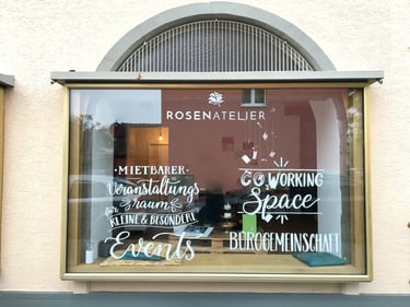 Shop window of Rosenatelier showing coworking space and event room rental services in German.