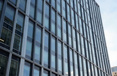 An architectural photograph of a sleek North American office building exterior during the day. Clean lines of steel and glass reflect a clear sky, symbolizing transparency and modern efficiency.