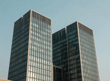 Modern architecture of a financial center in Mumbai, showcasing sharp lines and muted steel teal glass panels under a clear sky.