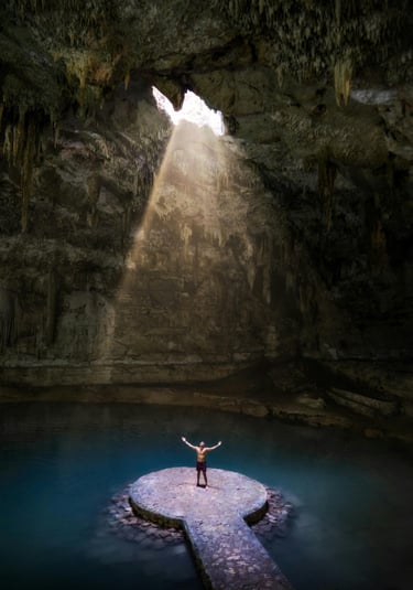Cenote en Riviera Maya con entrada de luz y persona parada en una plataforma