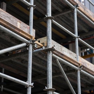 A detailed shot of complex scaffolding joints and metal poles on a large-scale building site in a Northern European / British city.